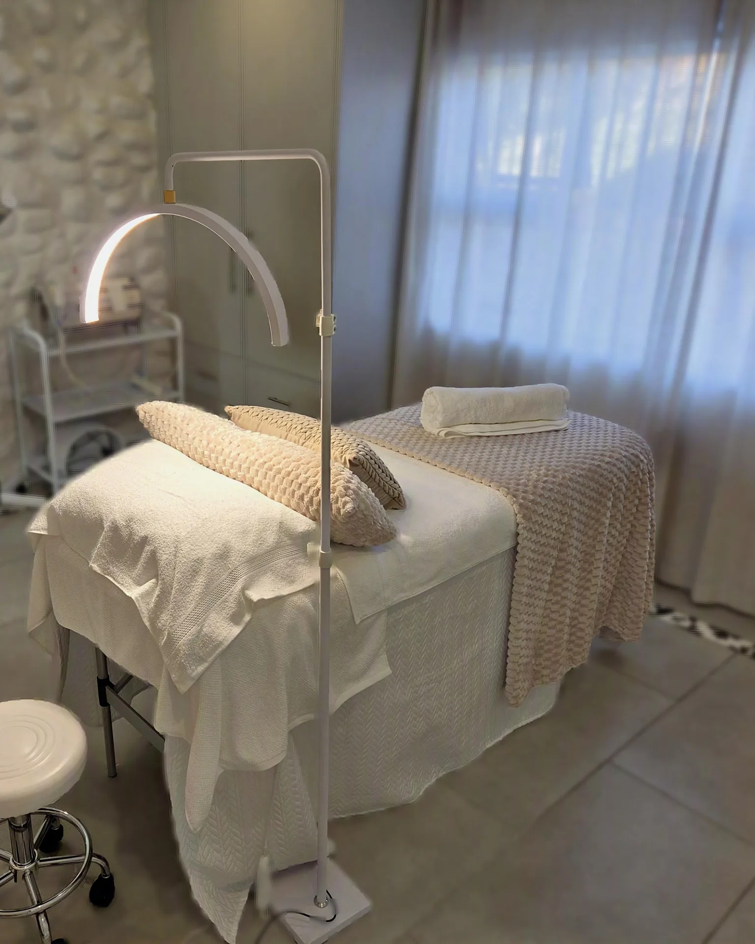 The treatment room at Skin Science Aesthetics – the bed made up under a soft lamp, warm light and neutral tones